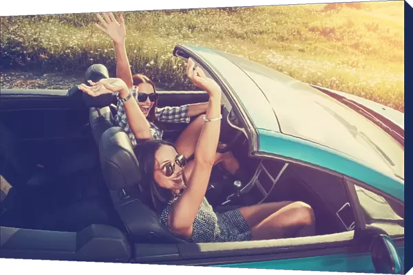 Two attractive young women in a convertible car