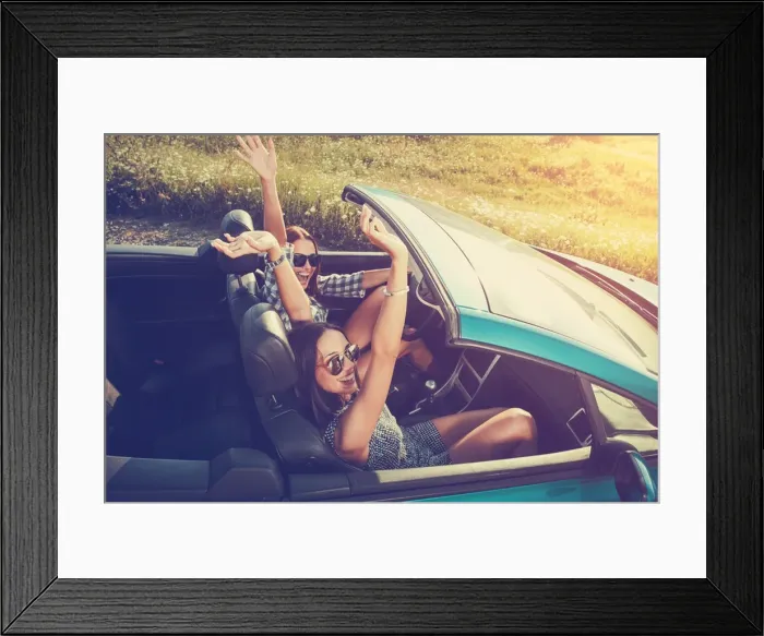 : Two attractive young women in a convertible car : Two attractive young women in a convertible car